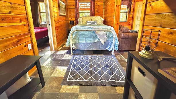 A wooden cabin bedroom with a bed, a bench, and a dresser. - Mossback Outfitters located in Wright City (Wright City)
