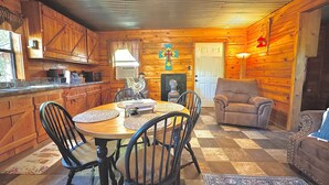 A cozy cabin interior with a wooden dining table, chairs, a fireplace, and a couch. - Mossback Outfitters located in Wright City (Wright City)