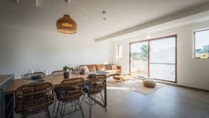 Un espacio de estar moderno con comedor, asientos y un gran ventanal corredera que da a un área exterior.