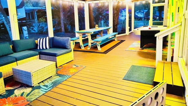 An indoor patio area with a wooden deck, a sofa, a table, and benches.