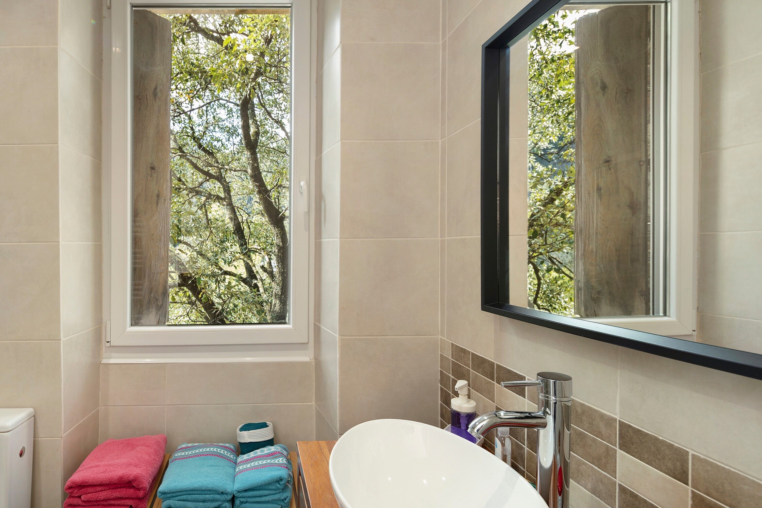 A bathroom with a window, a sink, and towels.
