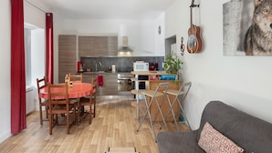 Cocina moderna con microondas, estufa y armarios. Hay una mesa de comedor con sillas y un sofá en la sala.