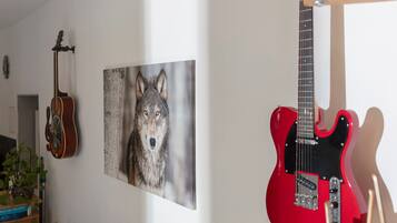 Una habitación con una guitarra, un cuadro con la imagen de un lobo y una guitarra eléctrica roja.