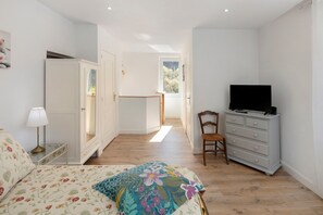 A bedroom with a bed, a dresser, a television, and a window.