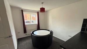 A small, modern kitchen with a round black table, a red hanging light, and a window with curtains. - 4 Bedroom House Sleeps 8 - Free Parking - Garden (Aylesbury)