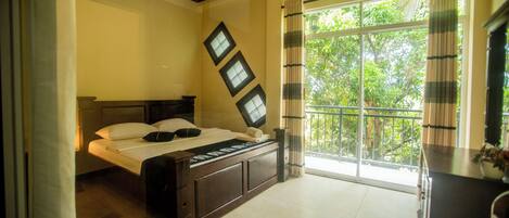 A bedroom with a bed, a window with curtains, and a ceiling fan.