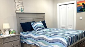 Ein Schlafzimmer mit Bett, Nachttisch, Kommode und Deckenventilator.