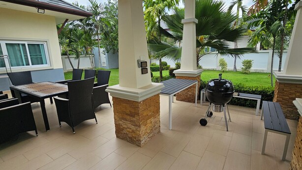 Eine Terrasse im Freien mit Grill, Esstisch und Stühlen.