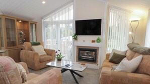 A living room with two sofas, a coffee table, a fireplace, and a TV mounted on the wall. - Labernum (Preston)