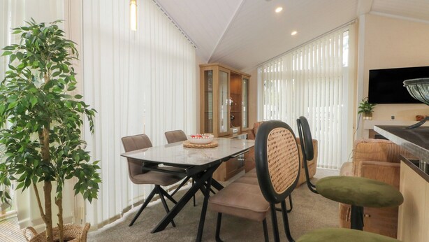 A modern dining area with a table, chairs, and a potted plant. - Labernum (Preston)