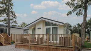 A single-story mobile home with a wooden deck, a covered porch, and a gravel driveway. - Labernum (Preston)