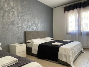 A bedroom with a bed, a nightstand, and a window with curtains. - Venetian Breeze (Mestre)