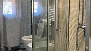 A modern bathroom with a glass-enclosed shower, a toilet, and a bathtub. - Venetian Breeze (Mestre)