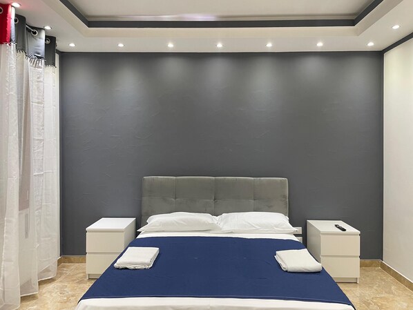 A bedroom with a bed, two nightstands, and a grey headboard. - Venetian Breeze (Mestre)