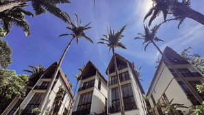 Un bâtiment moderne doté de nombreux balcons et de grandes fenêtres, entouré de palmiers.