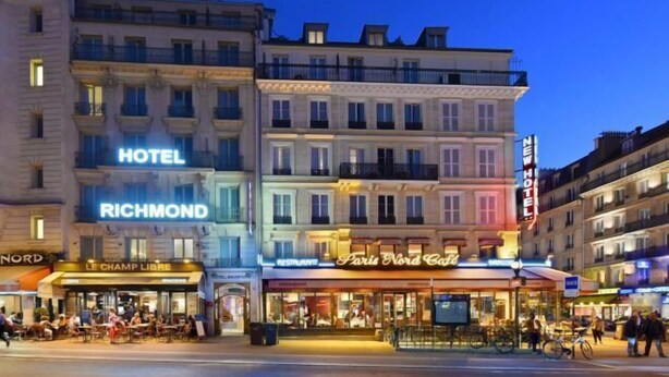 Un hotel con un cartello 'HOTEL RICHMOND', un ristorante chiamato 'Paris Nord Cafe' e un cartello 'NORD'.