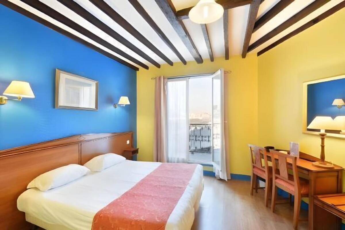 Una habitación de hotel con una cama, un escritorio y una silla.