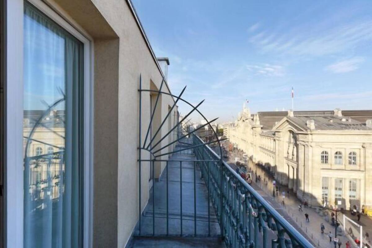 Una escalera con barandilla de metal que conduce a un edificio de arquitectura clásica.