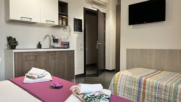 Ein Hotelzimmer mit einem Bett, einer Massageliege, einem Fernseher, einem Waschbecken und einem Kleiderschrank.