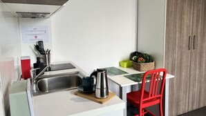 Eine kleine Küche mit Spüle, Wasserkocher und einem roten Stuhl.