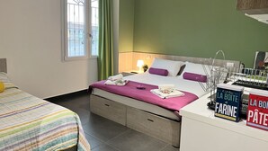 Ein Hotelzimmer mit Bett, Nachttisch, Fenster mit Vorhängen und Blick ins Freie.