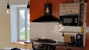 Una cocina con una isla central, horno Bosch, microondas y lámparas colgantes.