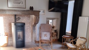 Una sala acogedora con chimenea, televisor, muebles de mimbre y una mesa de madera.