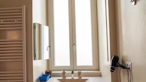 A bathroom with a white sink, a mirror, and a window with a view. - Palazzo delle Puglie B&B (Barletta)
