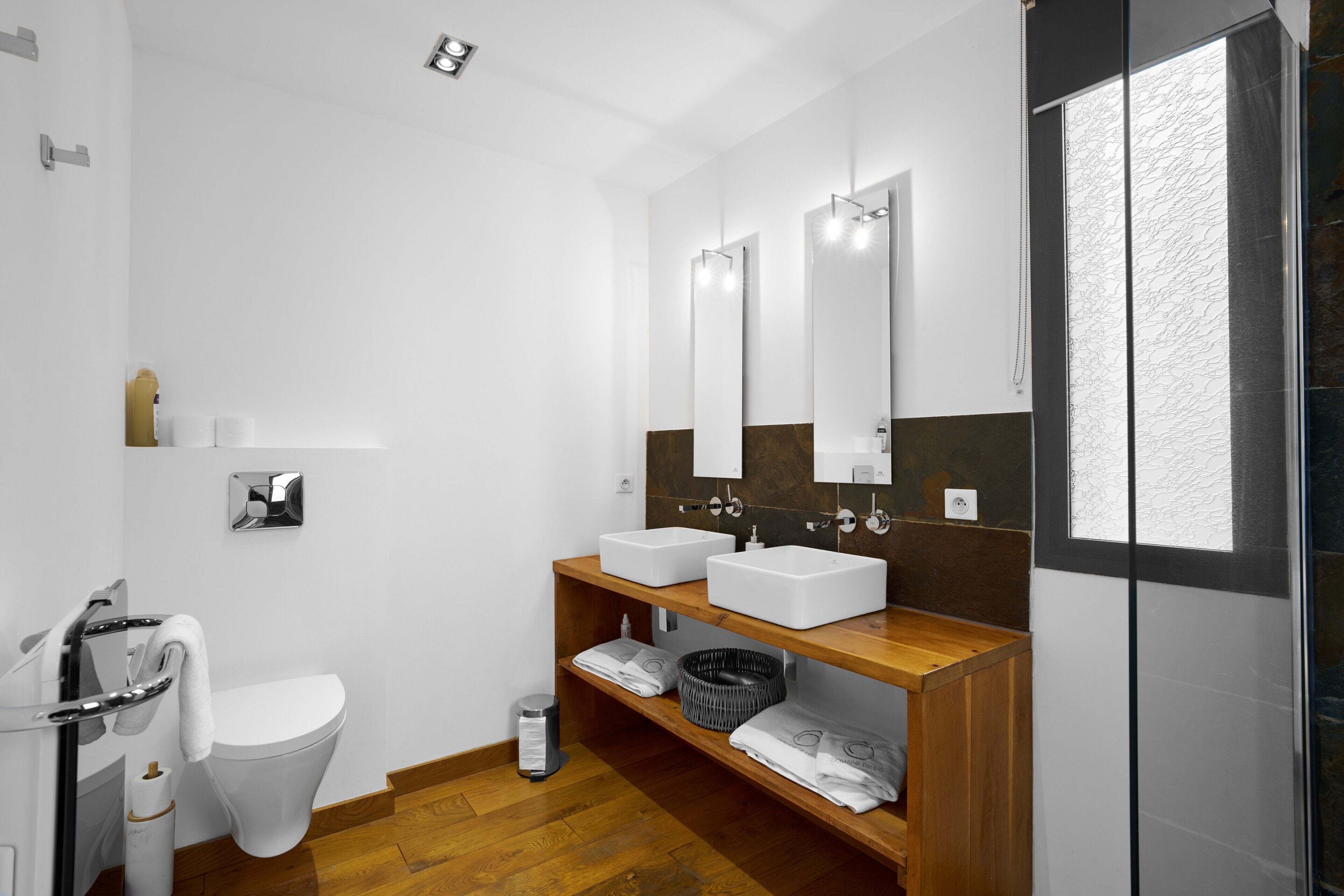 A modern bathroom with two sinks, a toilet, and a shower.