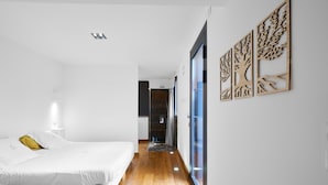 A bedroom with a bed, a nightstand, a wall-mounted lamp, and a wooden floor. - Loft Ôvebas at Domaine De L'ô (Eyraud-Crempse-Maurens)