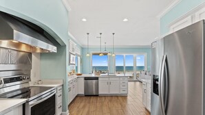 A modern kitchen with stainless steel appliances, a dishwasher, and a large island. - Seanile (Orange Beach)