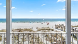 A beach view from a balcony with a wooden railing, sandy beach, and ocean. - Seanile (Orange Beach)