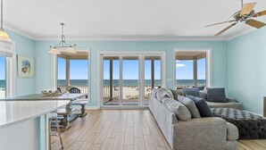 A spacious living area with a large window overlooking the ocean, a ceiling fan, and a light fixture. - Seanile (Orange Beach)