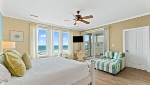 A bedroom with a bed, a ceiling fan, a TV, and a view of the beach. - Seanile (Orange Beach)