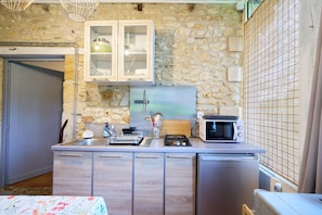 Una cocina compacta con pared de piedra, microondas, tostadora y lavamanos.