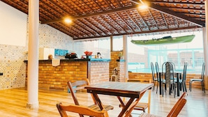 An indoor dining area with a brick wall, wooden ceiling, and a pool visible through the window. - Pousada Vila Lençóis e Sport (Barreirinhas)