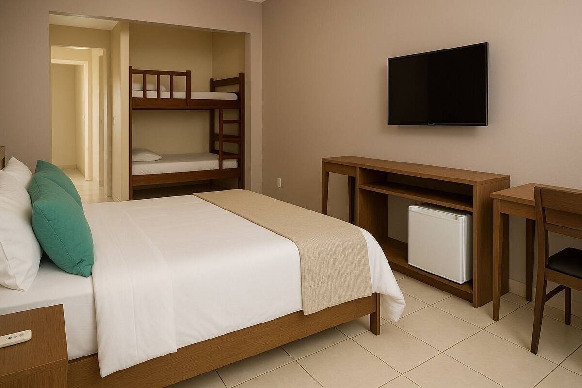 Een hotelkamer met een bed, bureau, televisie en een stapelbed.