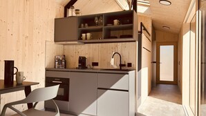 Una cocina compacta con paredes de madera, horno empotrado y cafetera.