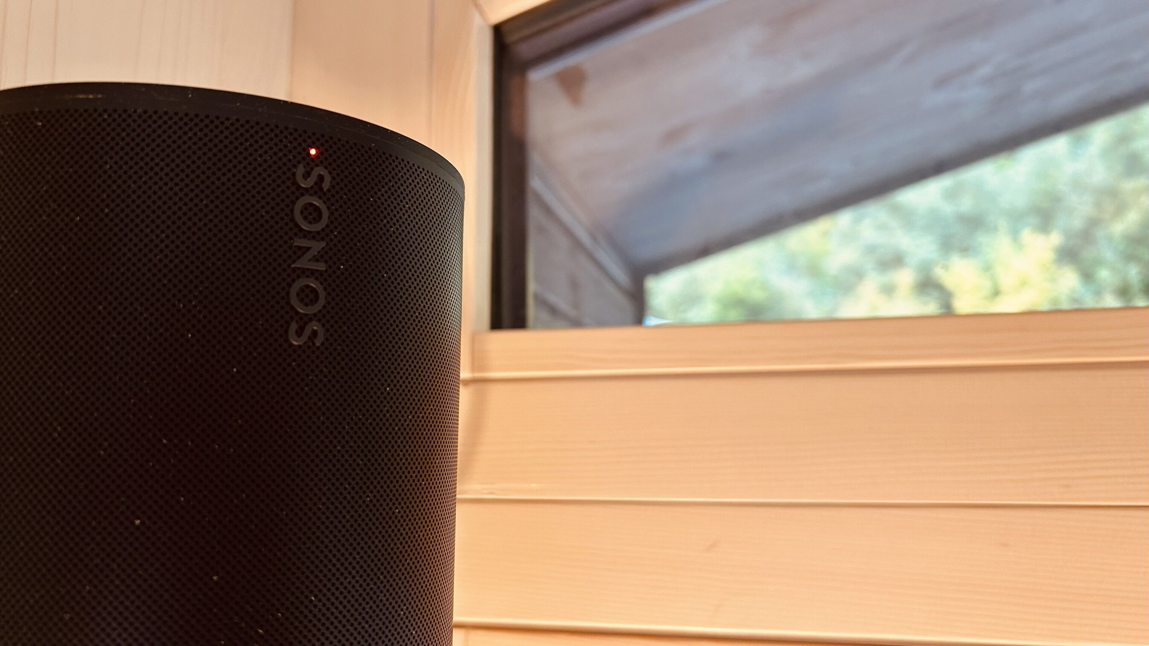 A black SONOS speaker near a window with wooden shutters.