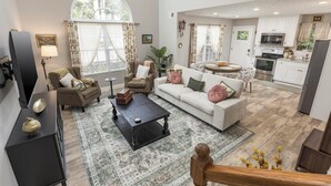 A spacious living room with a sofa, armchairs, and a coffee table. A kitchen is visible in the background with modern appliances. - La Casita- Trailside Retreat in Collegedale (Collegedale)