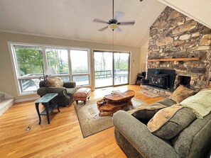 A spacious living room with a stone fireplace, large windows, and a cozy seating area. - Sugar Mountain Alpine Retreat - Your Ultimate Mountain Escape for Play and Relax (Sugar Mountain)