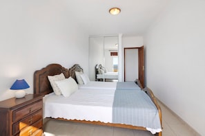 A bedroom with a bed, nightstand, lamp, and a mirror.