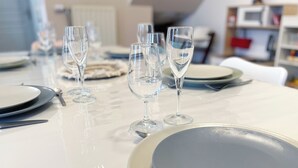 A dining table set with plates, glasses, and cutlery. - The Family House, spacious with outdoor area, children's play area, wifi and parking. (Cormicy)