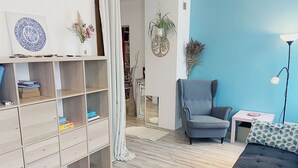 A modern living room with a grey armchair, a blue sofa, and a white side table with a lamp. - The Family House, spacious with outdoor area, children's play area, wifi and parking. (Cormicy)