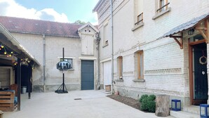 A courtyard with a basketball hoop, a wooden bench, and a small garden area. - The Family House, spacious with outdoor area, children's play area, wifi and parking. (Cormicy)