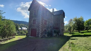 Un bâtiment en pierre avec une porte rouge et un escalier menant à l’entrée.