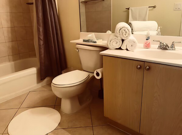 A bathroom with a toilet, a sink, a bathtub, and a mirror. - I Love It Coral Way Apartments (Miami)
