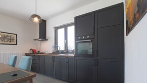 A modern kitchen with dark cabinets, a wooden countertop, and a dining area with a table and chairs.