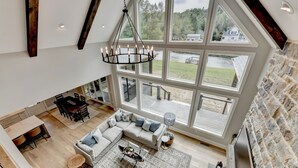 A spacious loft with a large dining area, a cozy seating area, and a view of the surrounding landscape through expansive windows.