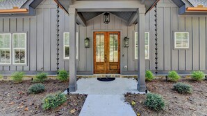 A house with a front porch, a wooden double door, and a stone pathway leading to the entrance.